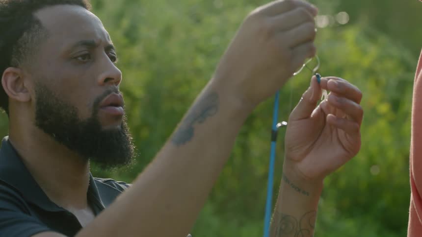 A man threads fishing line on a pole
