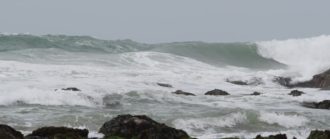High ocean waves crashing on a rock strewn beach