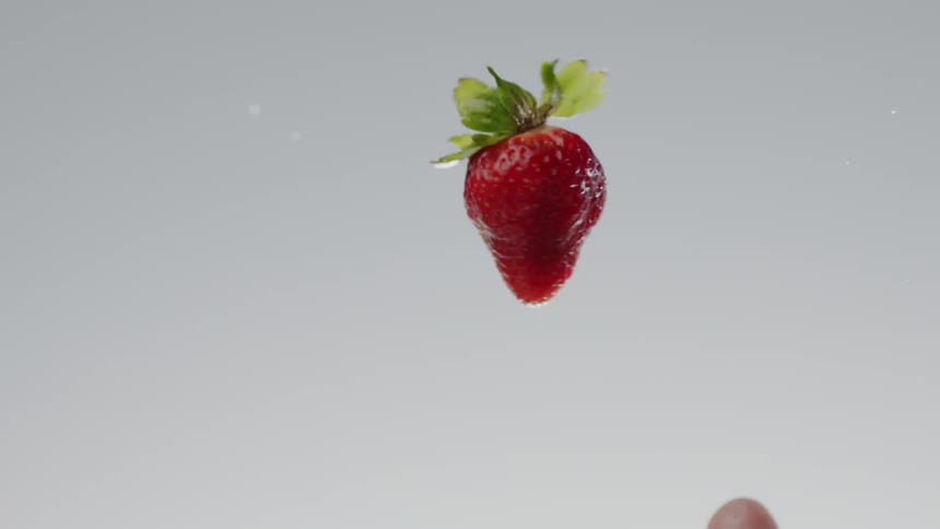 Hand tosses a strawberry in the air