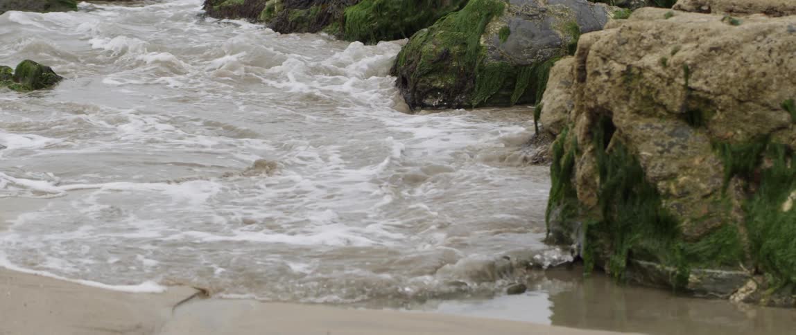 Ocean waves flow around rocks on a beach