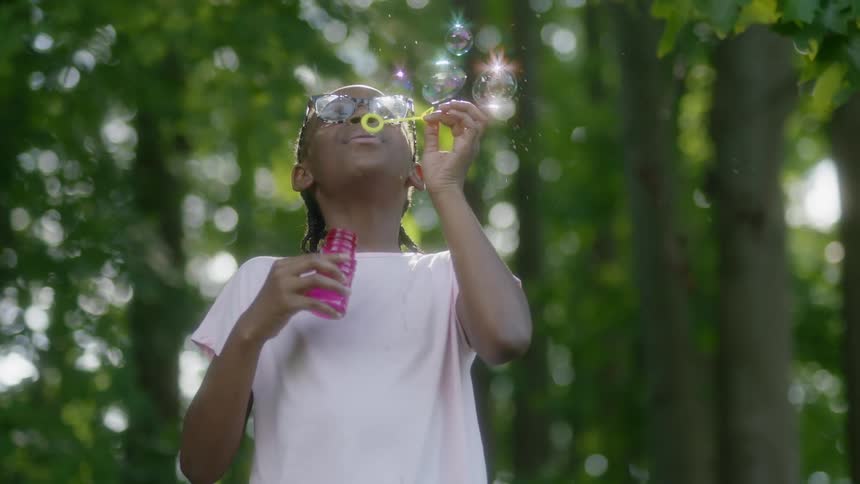 Child is blowing bubbles outside