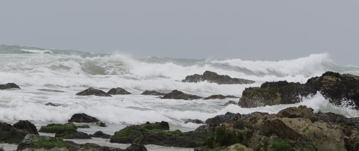 Waves are crashing onto rocks on the shoreline