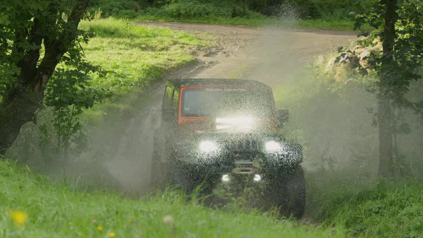 Jeep driving through the woods splashes through water