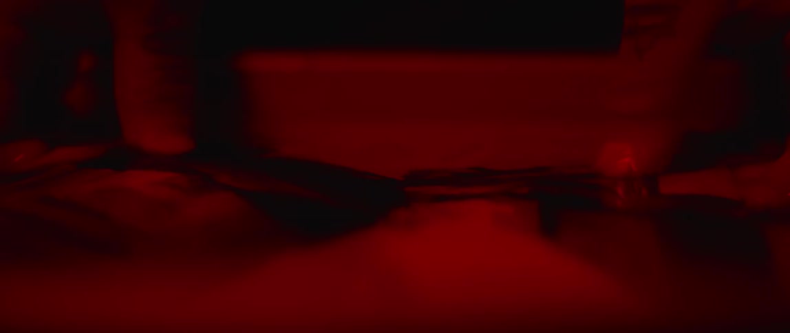 Person in dark room pulls pictures from chemical bath