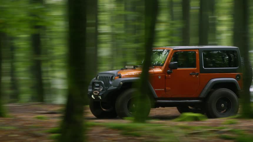 A four wheel drive car drives through a forest