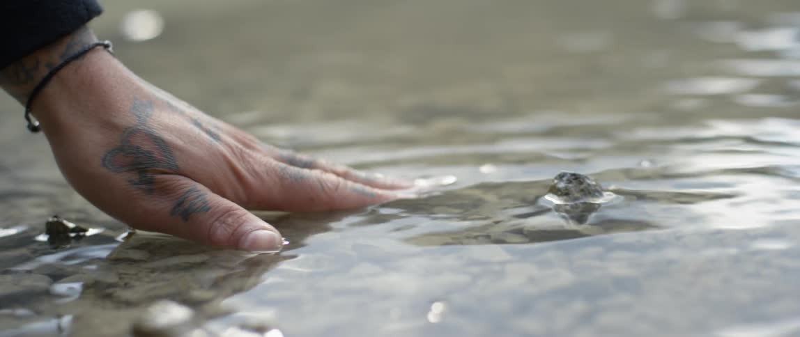 A hand is reaching into a shallow river