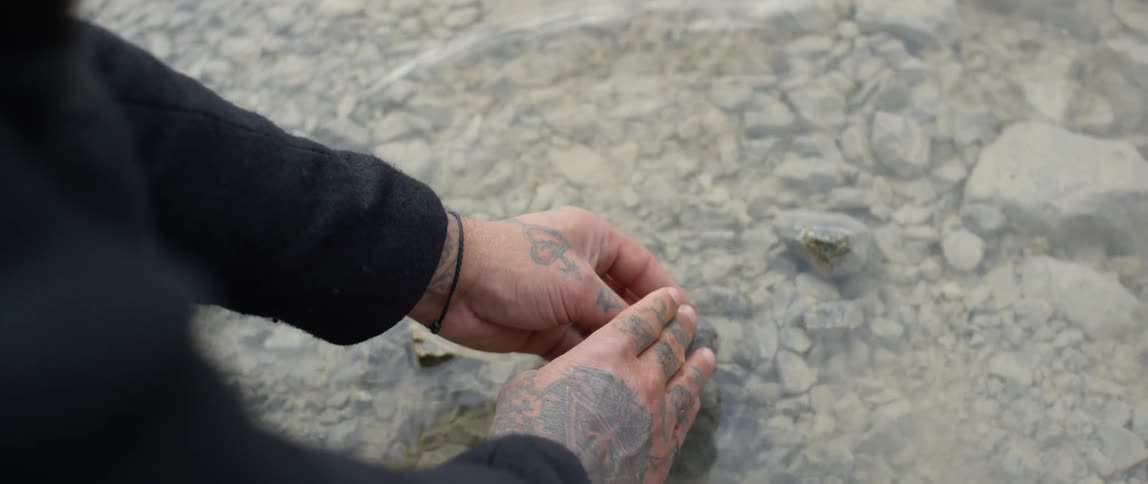 A person washes off a stone in a lake