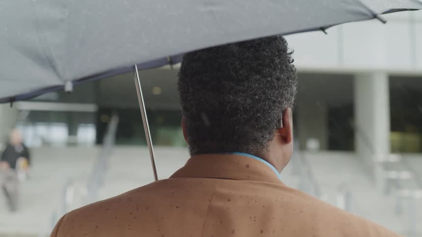 Man stands outside holding an umbrella