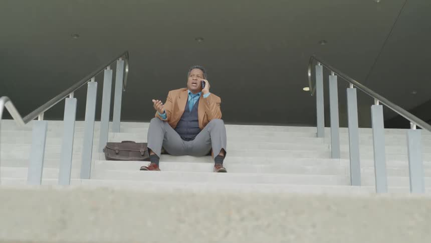 A man sits on the steps talking on his phone