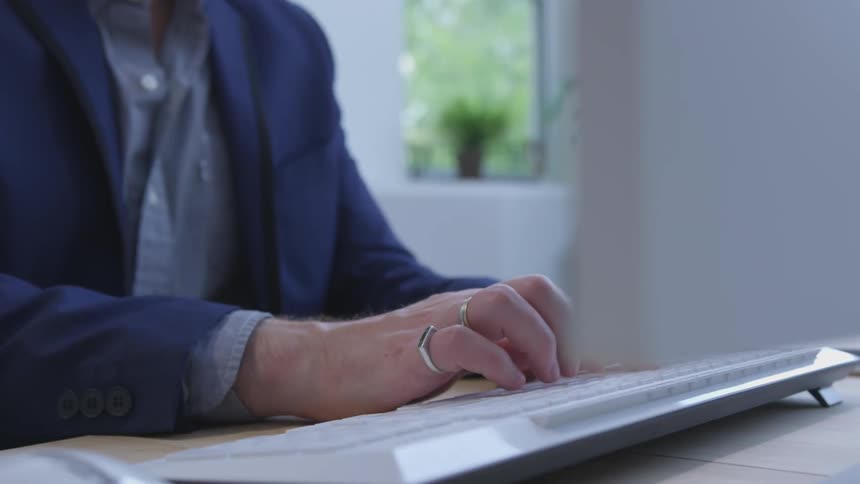 Person wearing blazer types on keyboard
