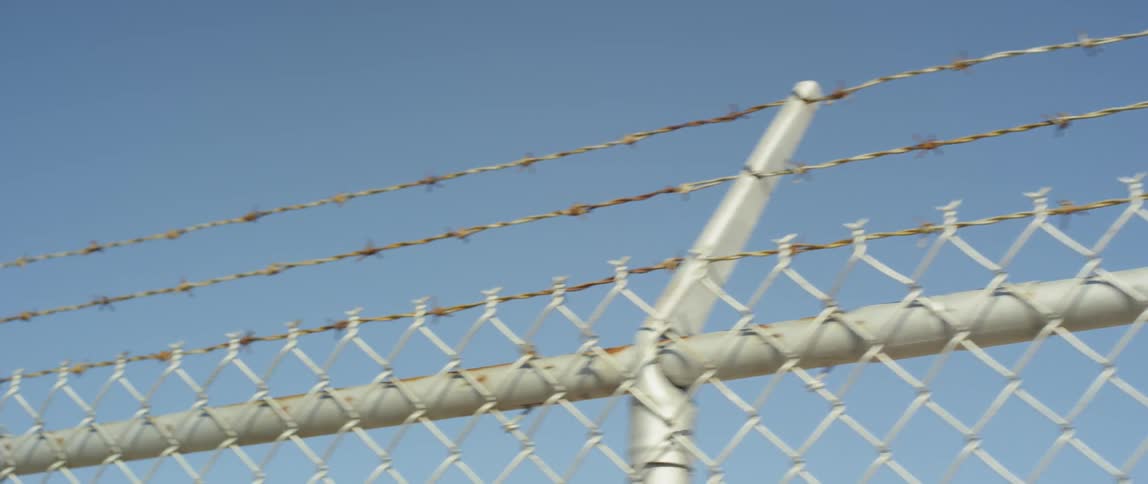 The top of a silver barbed wire fence