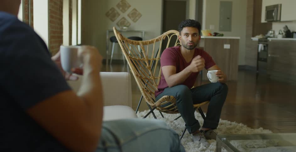 Two men sit down and have a chat drinking coffee in the living room