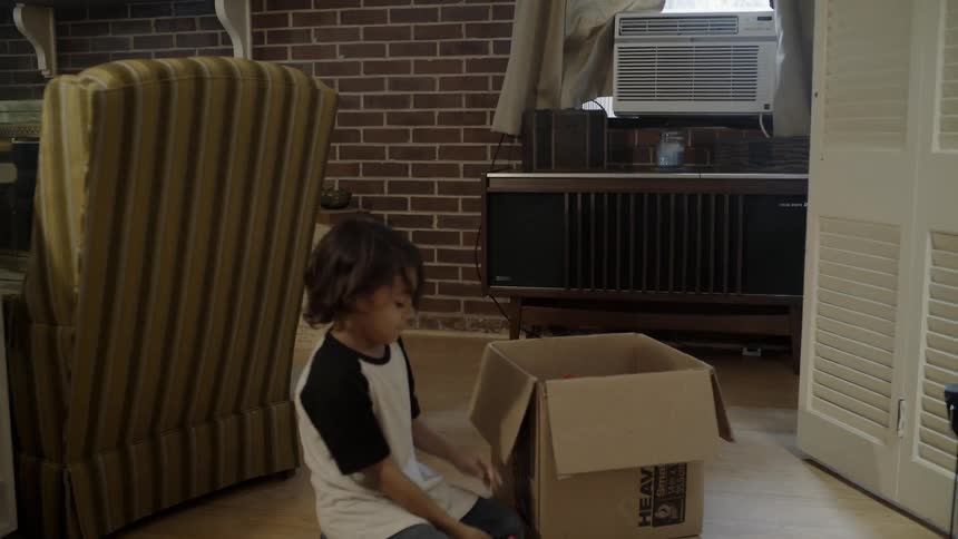 A child pulls a brown box and removes toys from the box