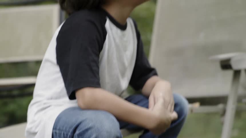 Child sits outside on a lawn chair in a yard