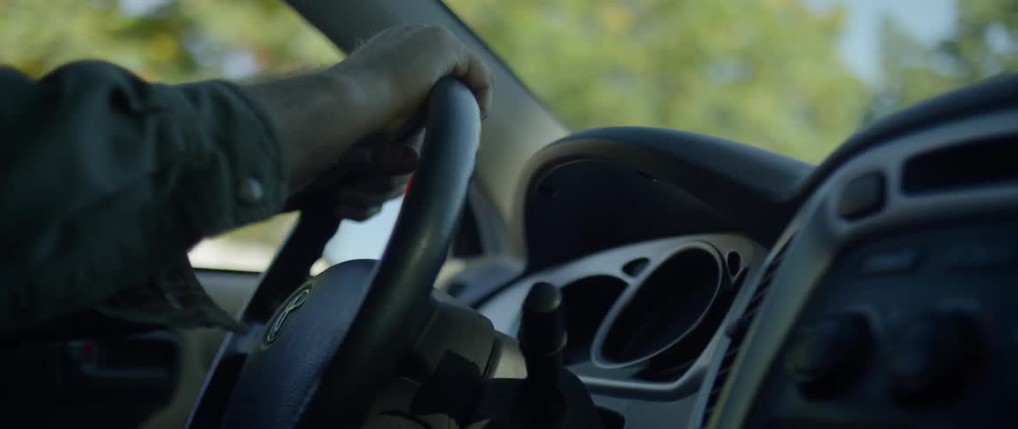 Man holding steering wheel drives his car on a sunny day