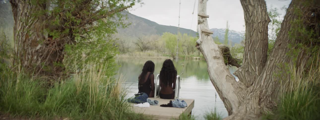 Two women sit on the pier of the lake