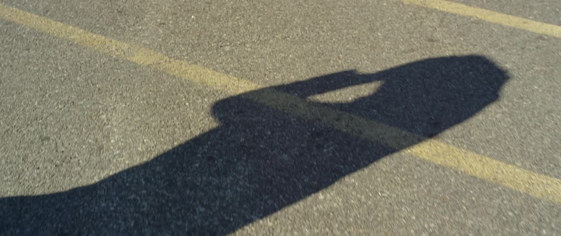 The shadow of a man walking and putting a cap