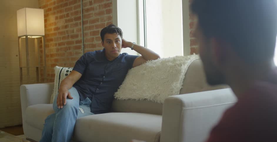 Two men talk while sitting in a living room