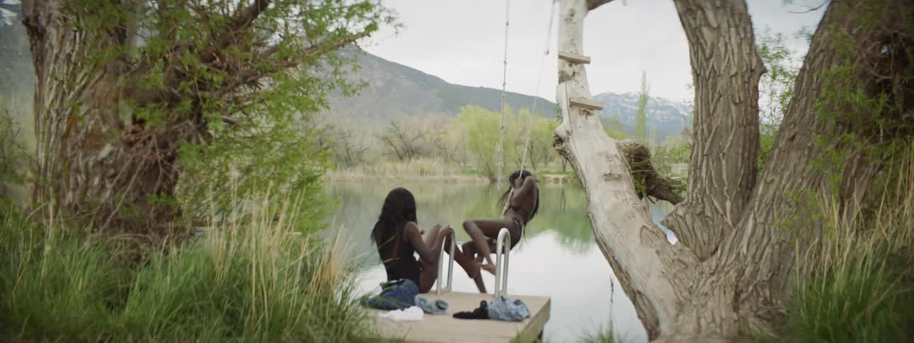 Woman swings on rope above lake