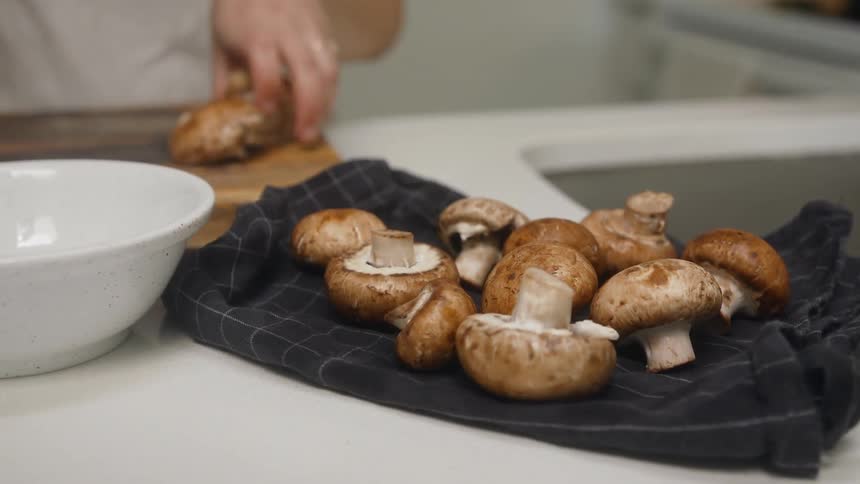 A woman cutting mushrooms on a kitchen
