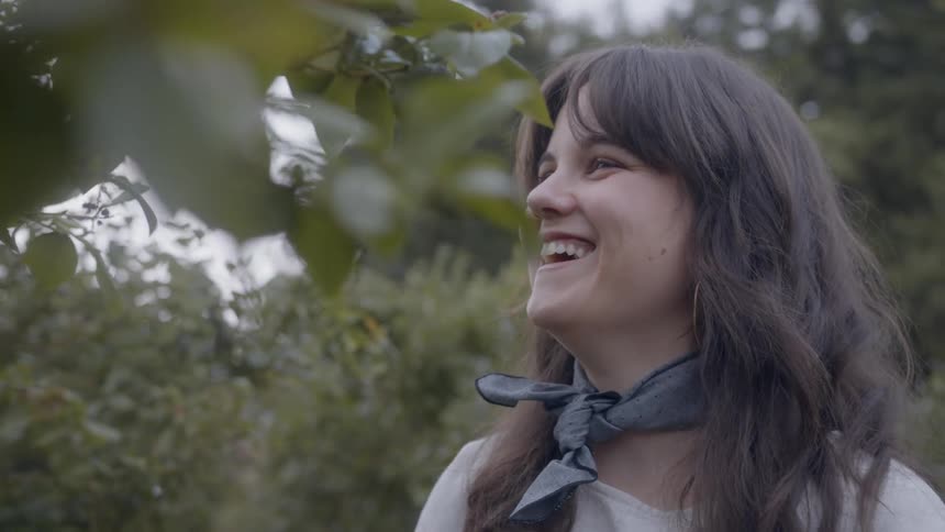 Woman laughing while picking something from a tree