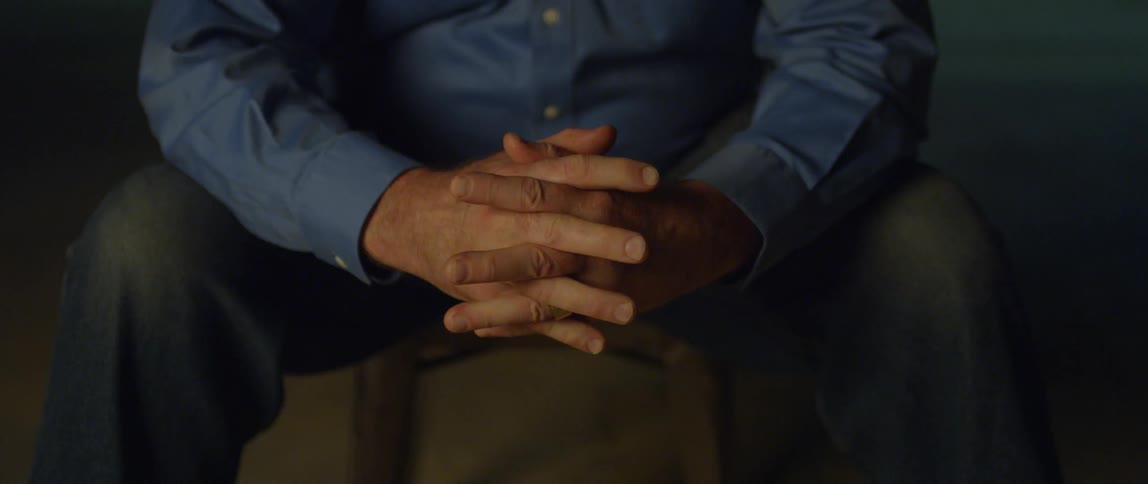 A man is sitting down and folding his hands together