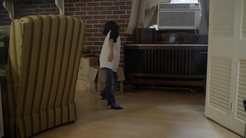 A boy pulls a box on the floor