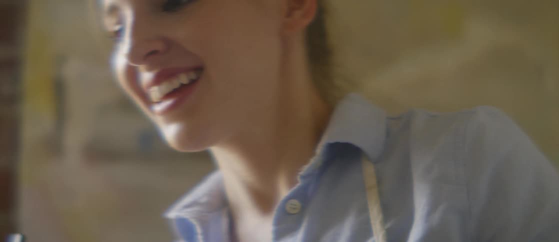 A woman smiling while wearing a paint apron