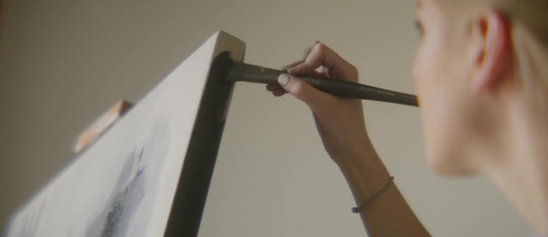 An artist painting black on the corners of a canvas