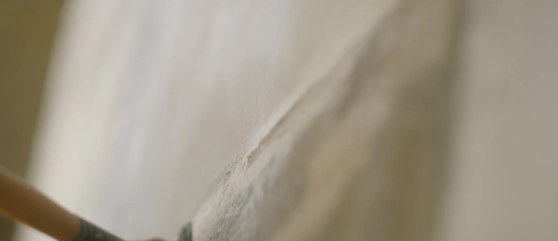 Persons' hand and arm using a flat paintbrush on canvas