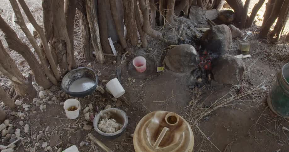 A smoldering fire in the dirt next to dishes