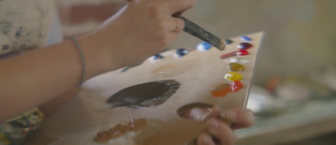 Person dabs a paintbrush on some paints