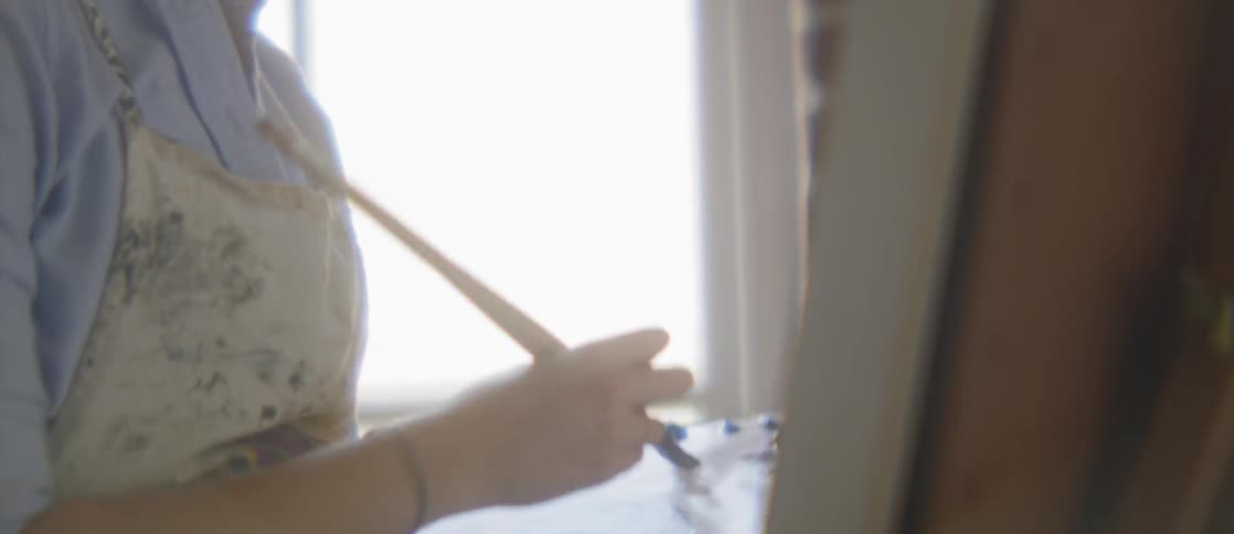 A woman painting in a bright room