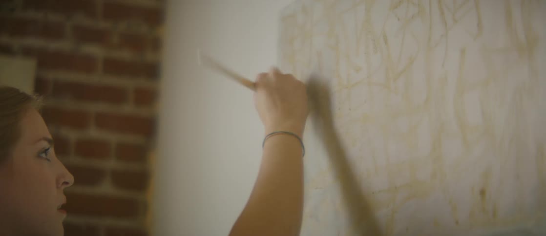 A woman is painting with a brush in the room
