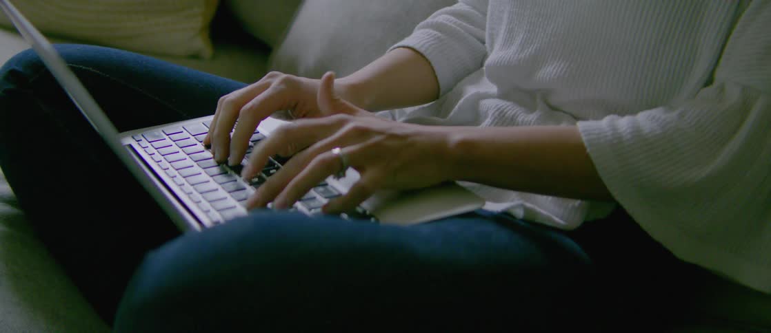 A person sitting on a sofa working on their laptop