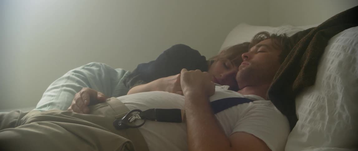A man and woman cuddle while napping in bed