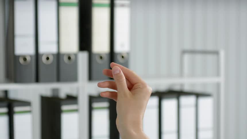 A hand throwing a paper plane on an office