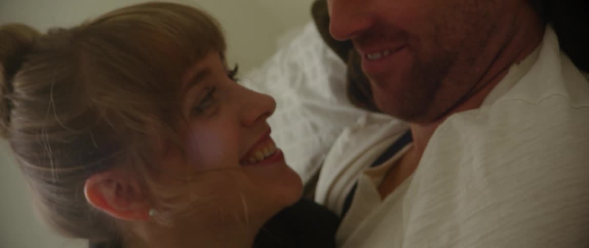 Woman and man snuggle in bed