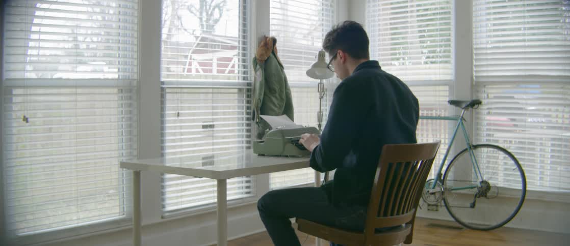 A writer works on a typewriter at a desk