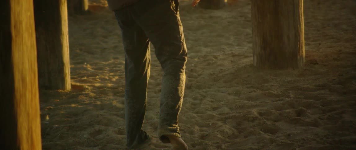 A man walks barefoot on sand