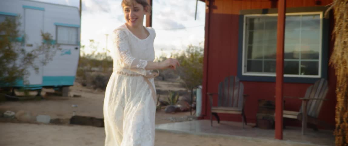 Woman runs out of painted red house in dress