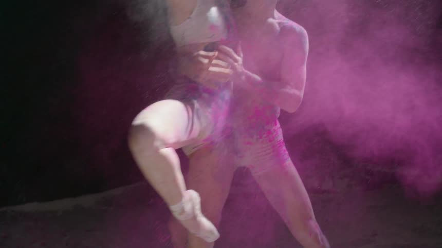 Two people dance and are hit with colored powder