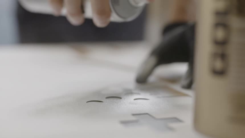 A man spray paints over a stencil