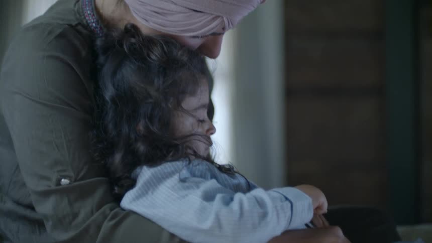 Woman and child are looking at a laptop indoors