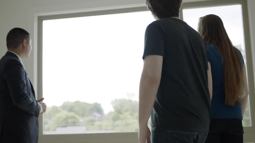 Man talks to man and woman who hold each other's  hand looking out of the window