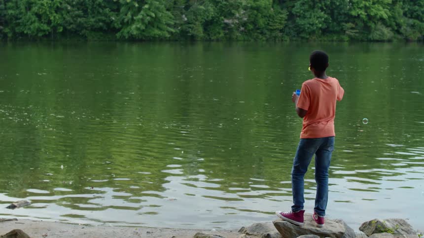 A person is blowing bubbles by a river
