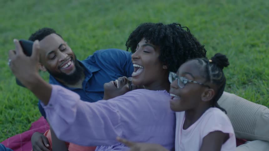 A family take a photo together in the grass