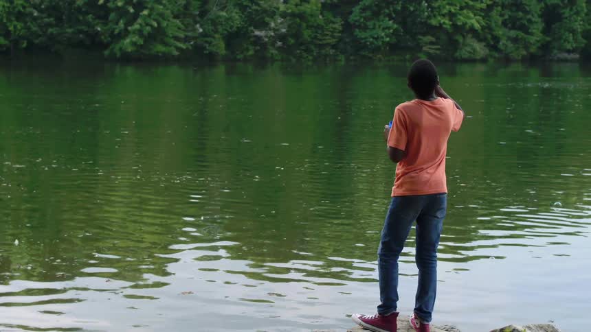 A boy is blowing bubbles by the river