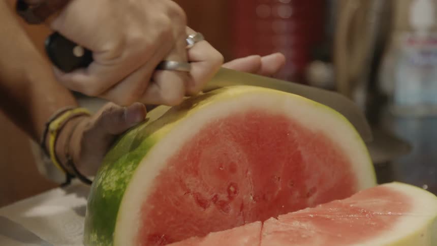 Person slices watermelon with sharp knife