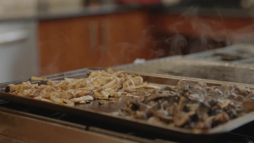 Trays of steaming food sit on a kitchen counter
